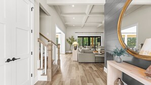 Ein geräumiger Wohnbereich mit Treppe, einer Sofagarnitur, einem Kamin und einem großen Spiegel.