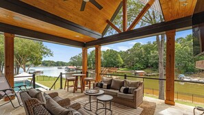 Un espacio al aire libre techado con muebles de mimbre, una piscina y vistas a un lago.