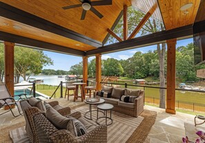 A covered outdoor area with wicker furniture, a pool, and a view of a lake. - New Saltwater Pool + Spa, Views | Wilson Hideaway (Mooresville)