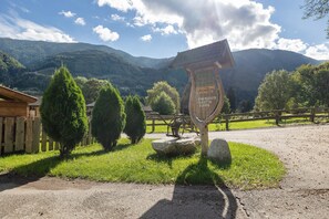 A signpost with text, a wooden fence, and a mountainous landscape.