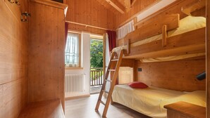 A wooden cabin room with bunk beds, a ladder, and a small table.
