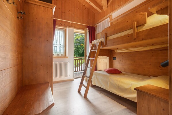A wooden cabin room with bunk beds, a ladder, and a small table.