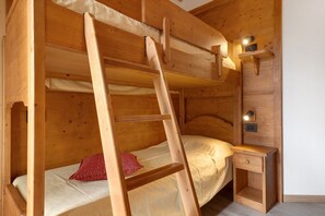 A bunk bed with a ladder, a bedside table, and a wall-mounted light fixture.