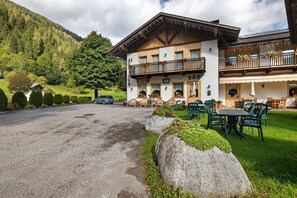 A hotel with a balcony, outdoor seating, and a mountain backdrop.