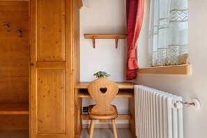 A wooden chair with a heart-shaped cutout, a white radiator, and a wooden shelf above it. - Room 'Camera Comunicant Letto A Castello' with Mountain View, Shared Garden and Wi-Fi (Caderzone Terme)