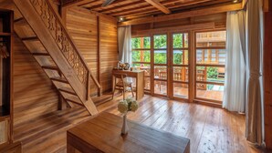 Een houten interieur met een trap, een eetgedeelte en grote ramen.