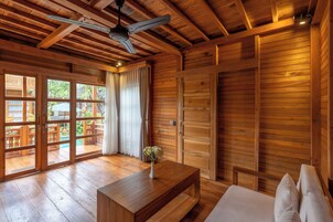 A wooden interior with a bed, a wooden table with a vase, and a ceiling fan.