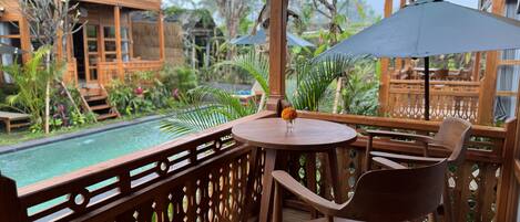 A wooden deck with a pool, wooden furniture, and a view of a wooden building.