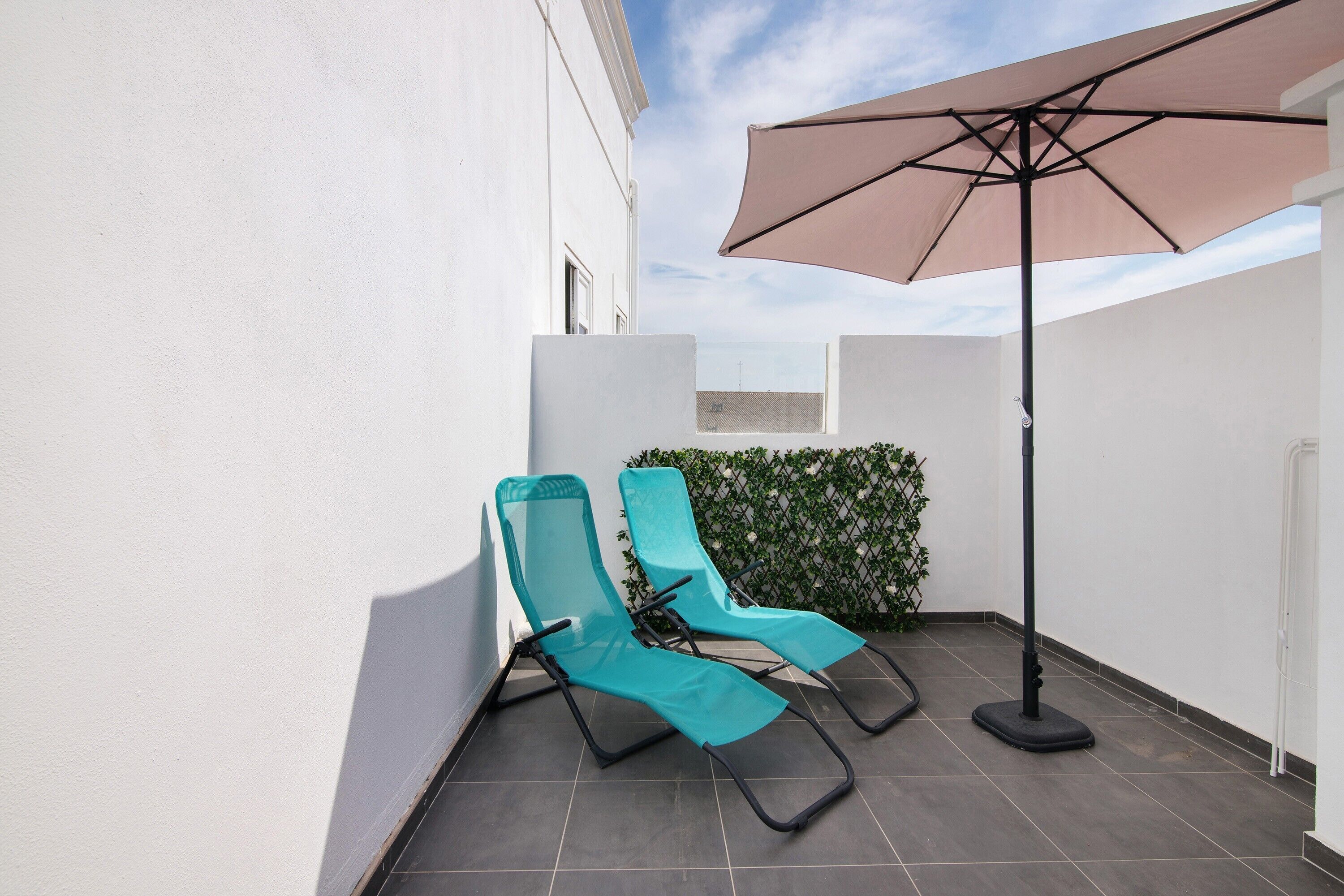 A small outdoor area with two lounge chairs and a large umbrella.