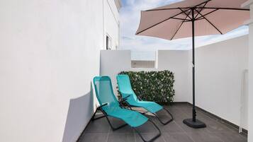 A small outdoor area with two lounge chairs and a large umbrella.