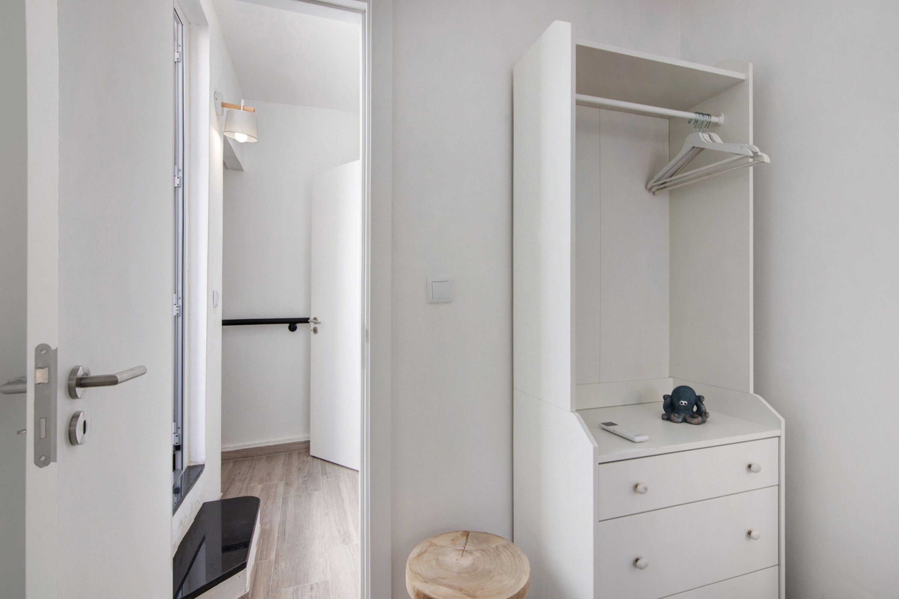 Et moderne badeværelse med et hvidt toiletbord, en rund skammel og et ophængt håndklædered.