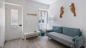 Een woonkamer met een bank, een lange zitbank, een lamp en decoratieve muurdecoratie van een zeepaard.