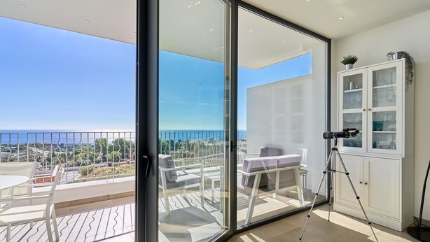 A balcony with a glass door, a tripod, and a cabinet with glass doors.