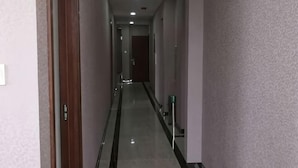 A narrow, well-lit hallway with a wooden door on the left and a mirror on the right. - Wanglong Leisure Hotel (Songbei Harbin University of Commerce, Ice & Snow World) (Harbin)