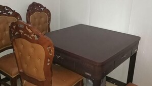 A dining table with four chairs, a dark-colored table, and a white wall in the background. - Wanglong Leisure Hotel (Songbei Harbin University of Commerce, Ice & Snow World) (Harbin)
