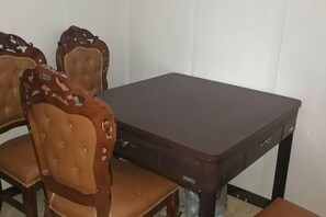 Een eettafel met vier stoelen, een donkerkleurige tafel en een witte muur op de achtergrond.
