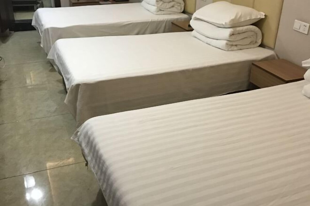 A hotel room with two single beds, each with a pillow and a folded blanket.