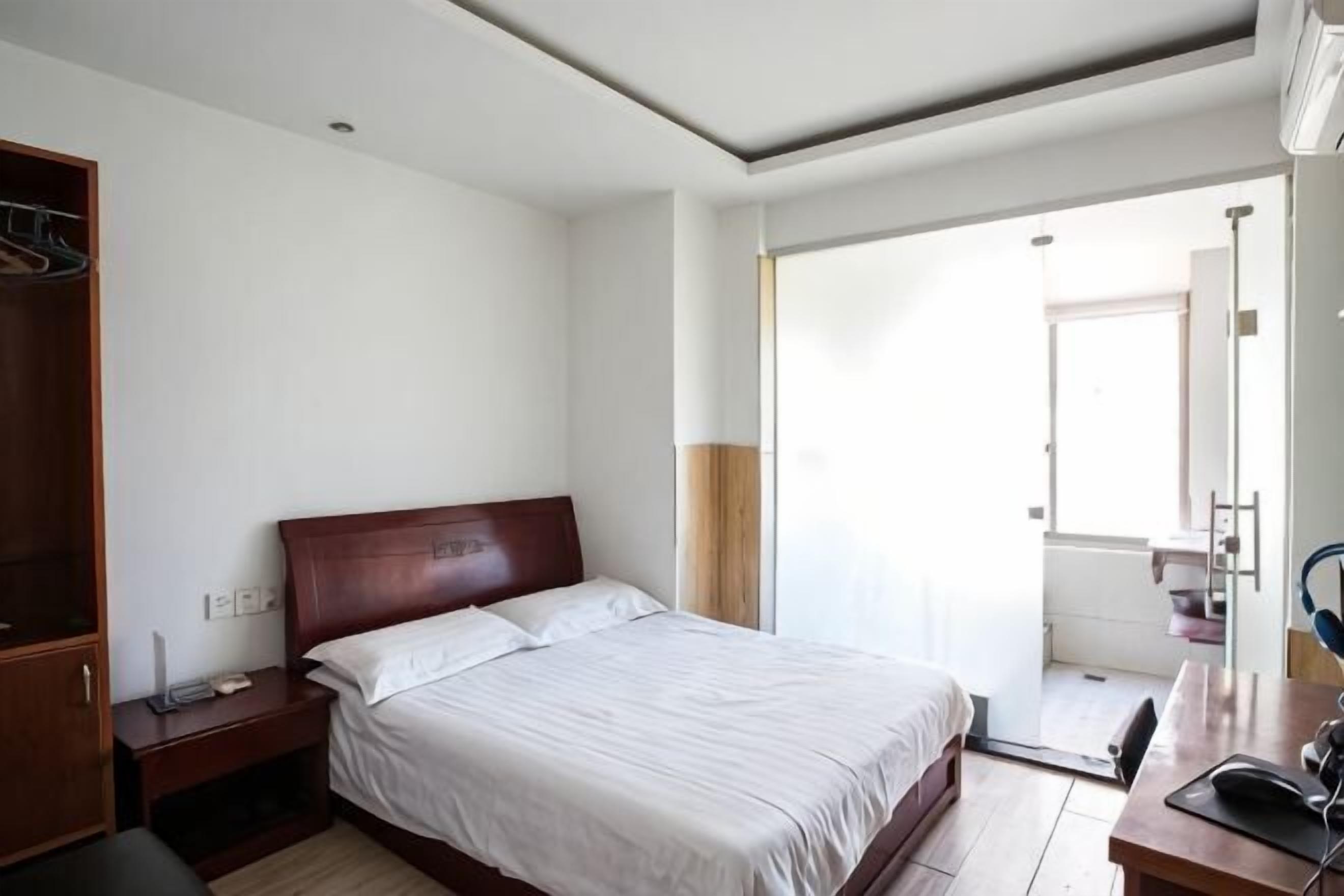 A bedroom with a bed, bedside table, and a desk with a chair.