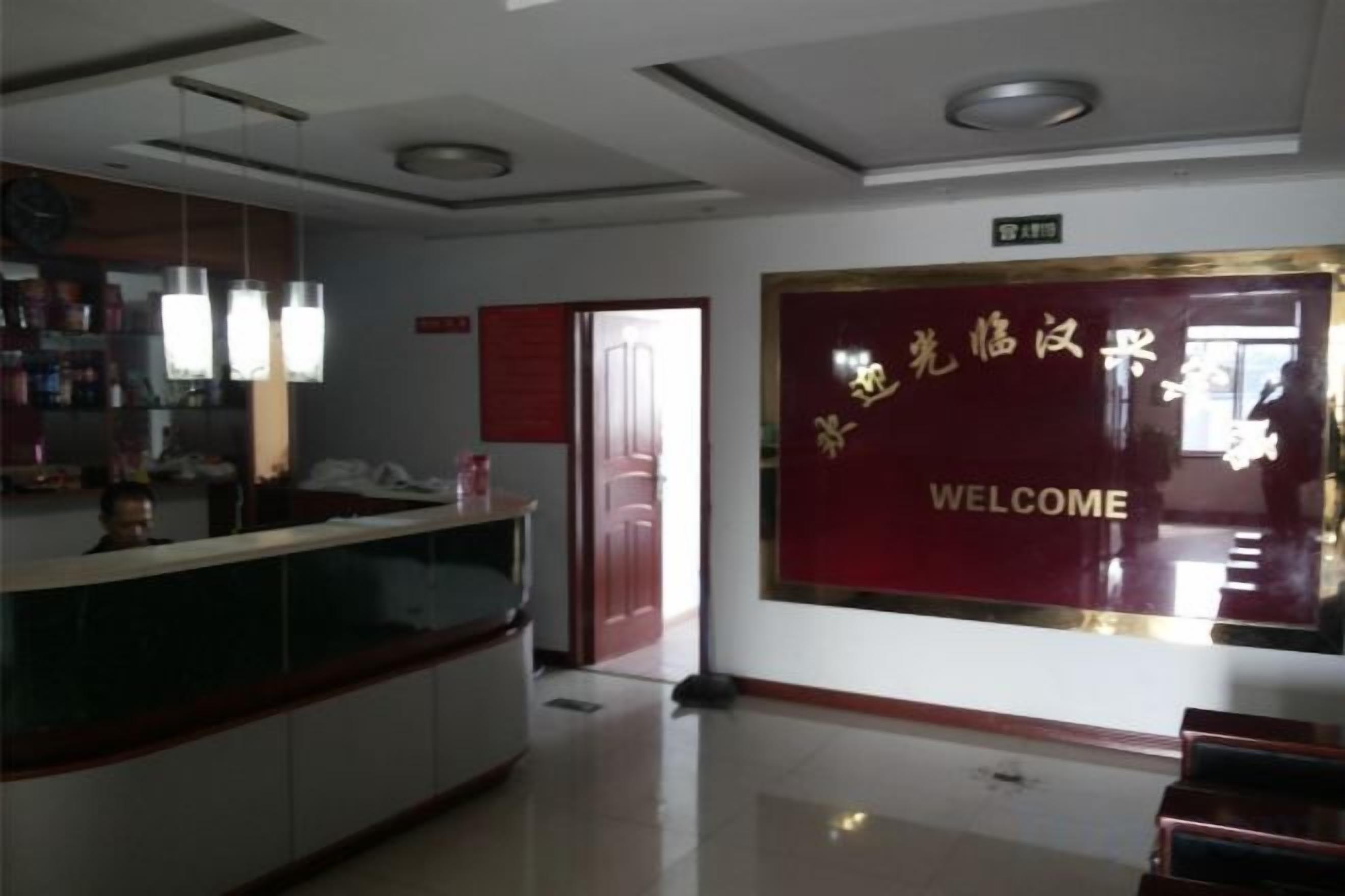 A reception area with a reception desk, a welcome sign, and a door leading to another room.