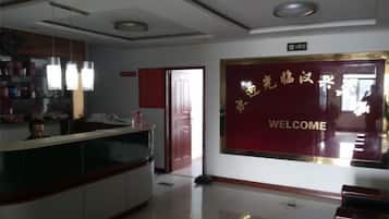 A reception area with a reception desk, a welcome sign, and a door leading to another room.