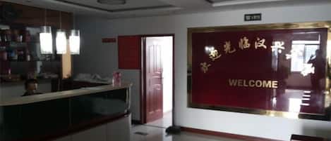 A reception area with a reception desk, a welcome sign, and a door leading to another room.