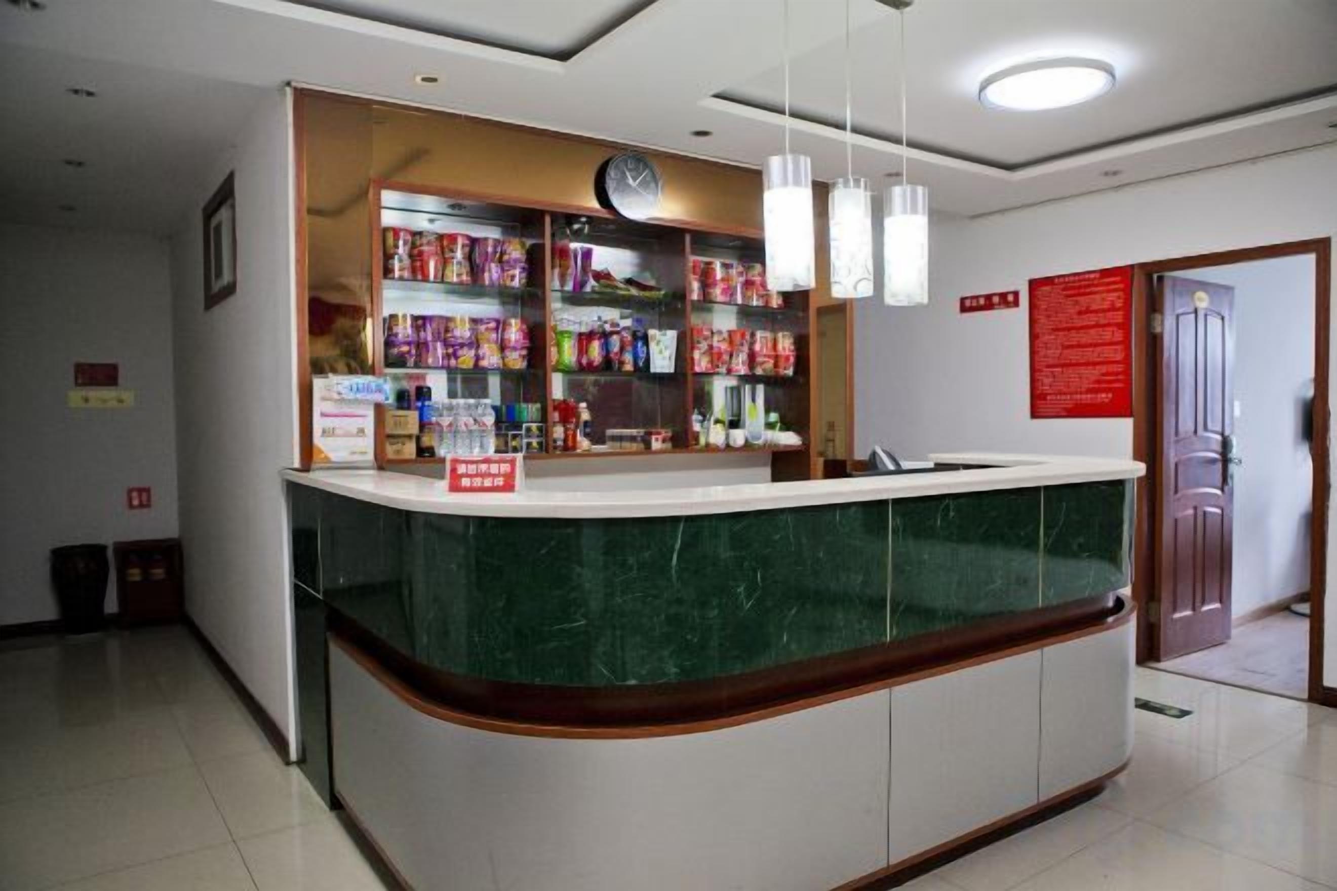 A reception desk with a green marble top, a clock above it, and shelves stocked with various items.