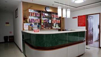 A reception desk with a green marble top, a clock above it, and shelves stocked with various items.