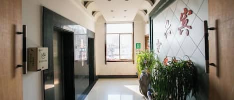A hotel corridor with a reception desk, a potted plant, and a wall with Chinese characters.