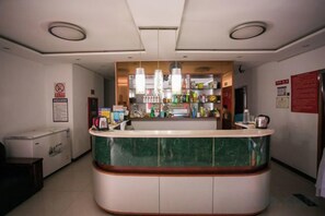 A reception area with a marble counter, a coffee machine, and a refrigerator. - Gangyue Hotel (Shaoxing)