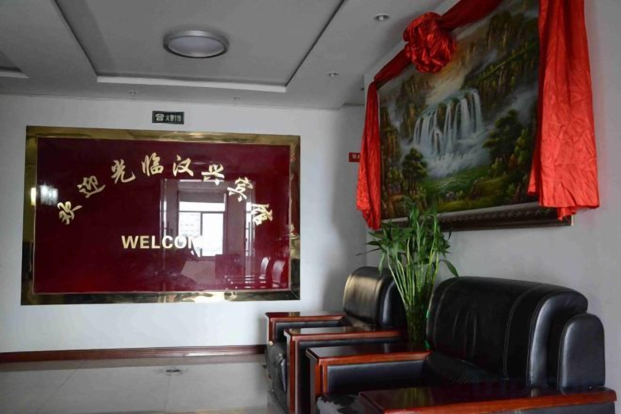 A reception area with a red welcome sign, a painting, and a seating area.
