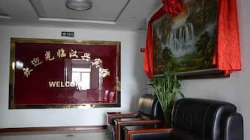 A reception area with a red welcome sign, a painting, and a seating area.