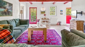 Una sala de estar acogedora con un sofá verde, una mesa de centro de madera y una alfombra colorida.