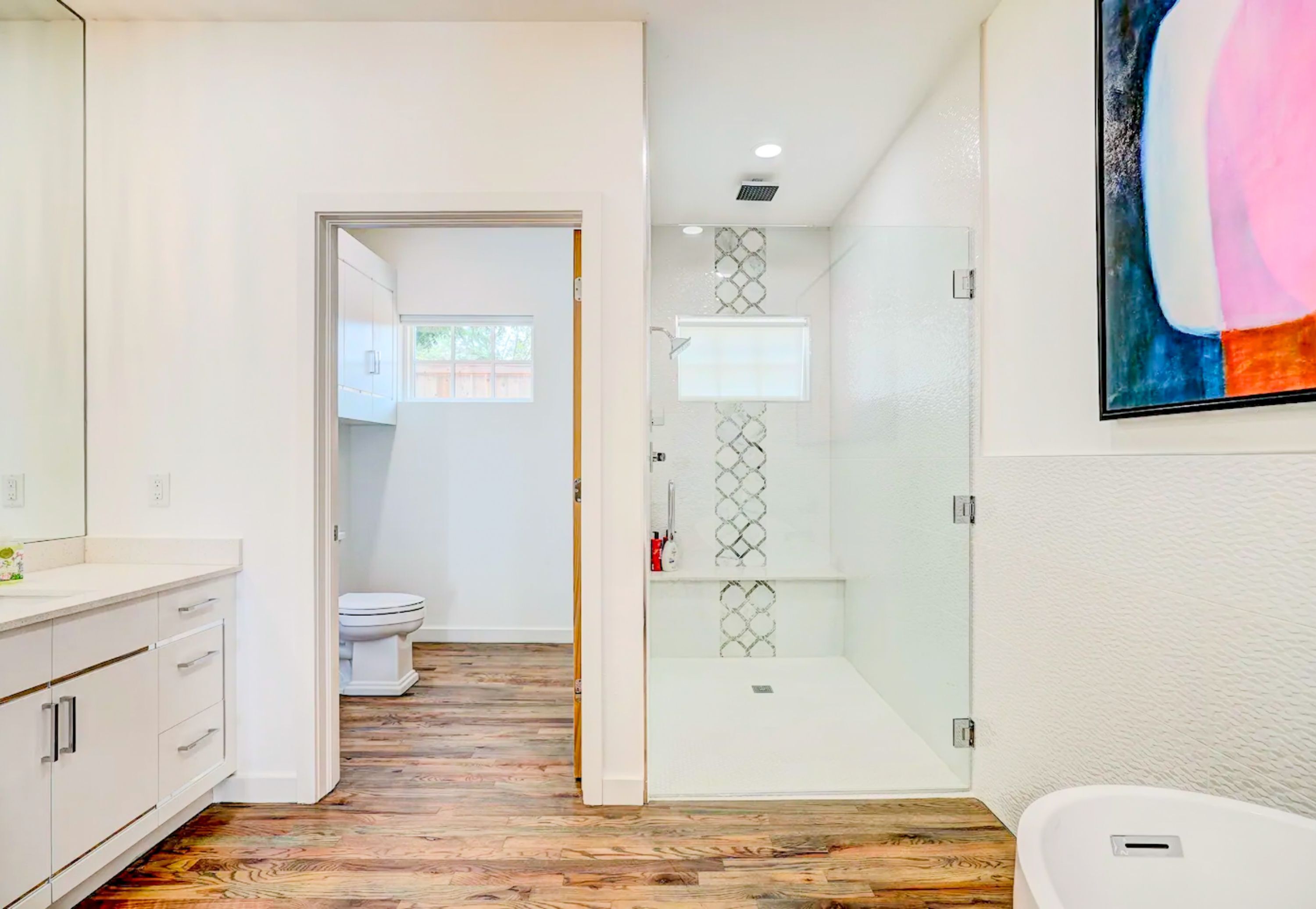 A modern bathroom with a shower, toilet, and a large mirror.