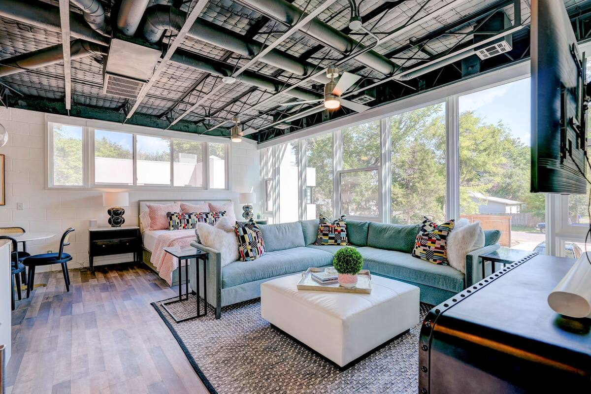 A modern living room with a large window, a sofa, a coffee table, and a TV.