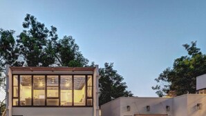 Una casa moderna de dos pisos con garaje, ventanas amplias y techo plano.