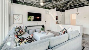 Una sala de estar moderna con un sofá gris, una mesa de centro y un televisor montado en la pared.