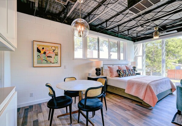 A bedroom with a bed, a window, a dining table with chairs, and a painting on the wall. - 6BR Near OU Campus I Great for Big Groups 1010 (Norman)