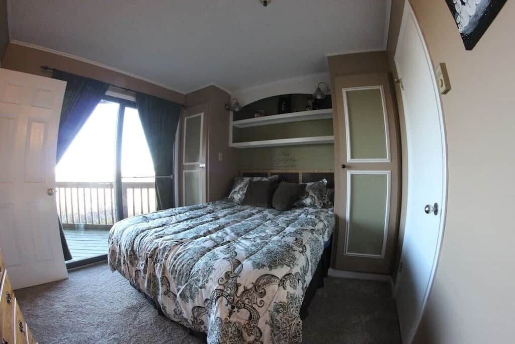 A bedroom with a bed, a wardrobe, and a door leading to a balcony.