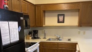 A compact kitchen with a refrigerator, stove, sink, and wooden cabinets. - Winterplace D105 Ski in Ski out condo First Floor (Ghent)