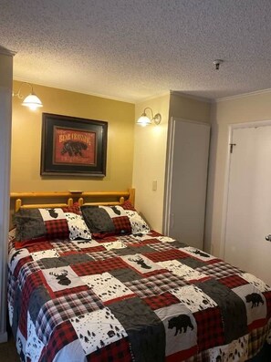 A bedroom with a bed, a framed picture on the wall, and a door. - Winterplace D105 Ski in Ski out condo First Floor (Ghent)