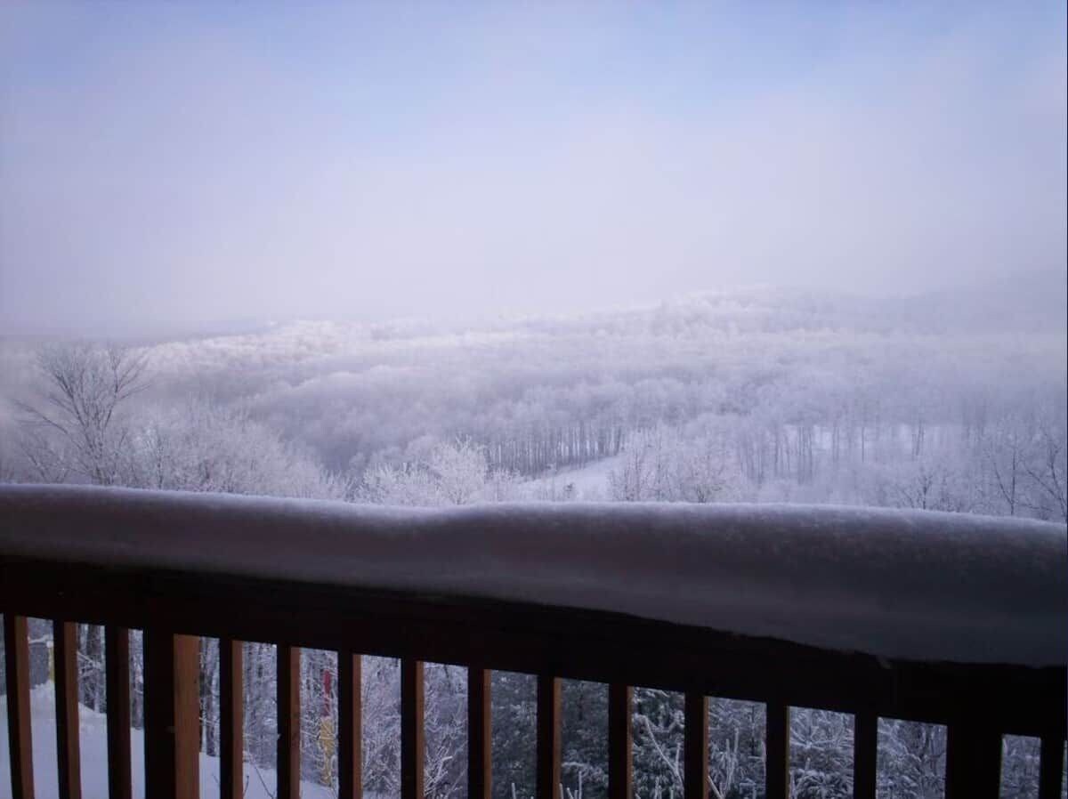 Un paysage enneigé avec une rambarde en bois au premier plan.