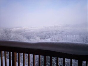 Eine verschneite Landschaft mit einem Holzafence im Vordergrund.