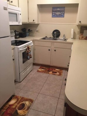 A kitchen with white cabinets, a microwave, an oven, and a sink.
