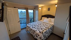 A hotel room with a bed, a door, a window, and a balcony.