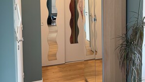 Un interior moderno con suelo de madera, un espejo grande y una planta en maceta.