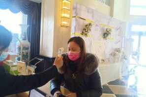 A person taking a temperature with a thermometer. - Tongcheng Wanquan International Hotel (Tongcheng)
