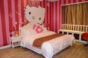 A bedroom with a large Hello Kitty wall decoration, a bed with white bedding, a nightstand with a lamp, and a window with curtains. - Tongcheng Wanquan International Hotel (Tongcheng)