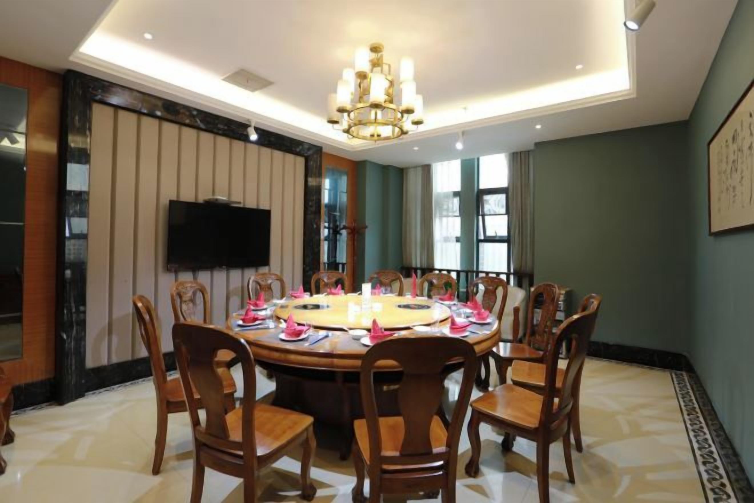 Un comedor con una mesa redonda, sillas y una araña.
