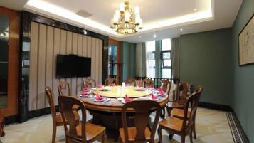 Un comedor con una mesa redonda, sillas y una araña.