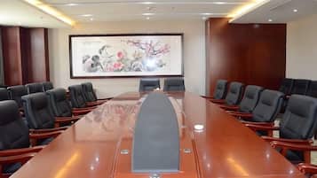 Un salón de conferencias con una larga mesa, sillas y una pantalla de proyector.